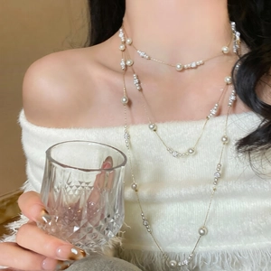 Detail of layered pearl necklace with crystals on a white sweater for elegant winter style