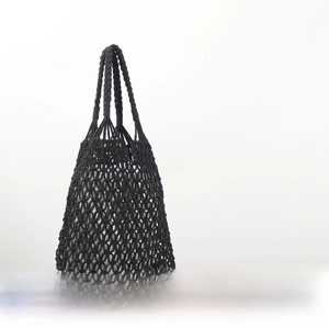 Macro detail of black handmade woven cotton rope bag with white inner lining and diamond mesh