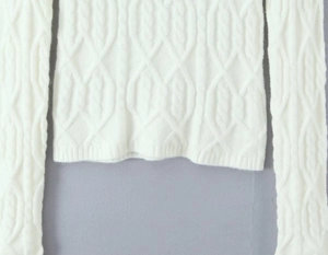 Close-up of white cable knit texture on a fitted sweater and matching skirt