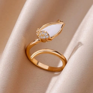 Detailed close-up of a gold tulip ring with white petal and zircons on beige silk fabric