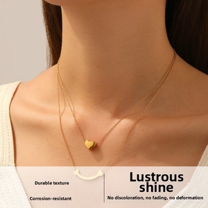 Gros plan d'un collier double épaisseur en or avec pendentif cœur sur le cou