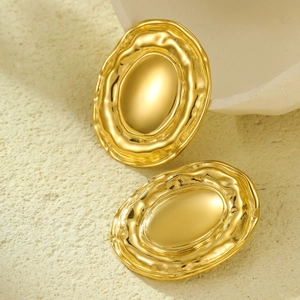 Macro detail of 18K gold plated oval earrings with irregular wave texture and polished finish