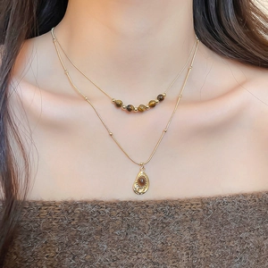 Detail of vintage double-layer gold necklace with tiger eye beads on model's neck