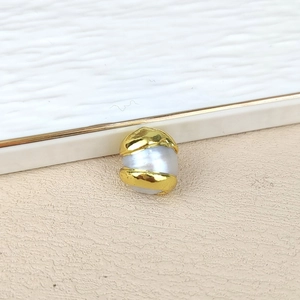 Macro view of a baroque freshwater pearl with irregular gold-plated metal texture wrap