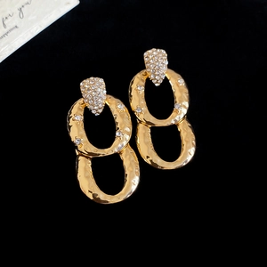 Detailed view of gold oval drop earrings with hammered metal texture and sparkling zircon
