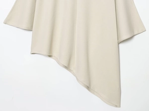 Close-up of the asymmetrical hemline and dense knit fabric on this beige two-piece set