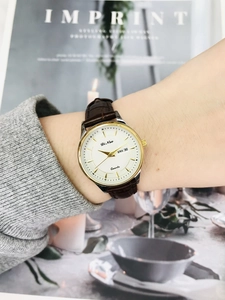 Detail of a quartz watch featuring a calendar display and brown leather alligator strap