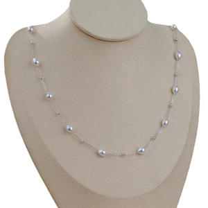Minimalist freshwater pearl necklace with silver accents on a beige display mannequin