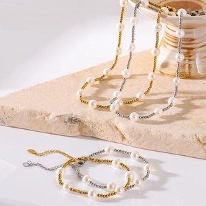 Elegant gold and silver pearl beaded necklace and bracelet set on stone background