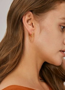 Detailed view of a gold tassel chain hoop earring worn on a model for a cyberpunk style