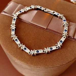 Dettaglio del bracciale argento con gemme blu e maglie a X su scatola in velluto