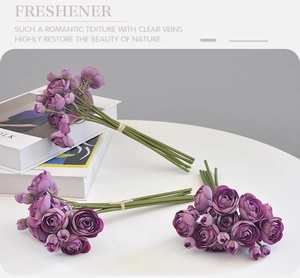 Detailed view of three purple silk rose bouquets on a minimalist white desk setting
