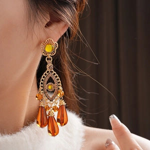 Detailed view of vintage gold tassel earrings with amber beads and floral design on model
