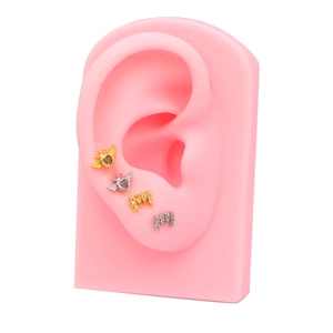 Détail de boucles d'oreilles cœur ailé et baguettes sur modèle d'oreille en silicone
