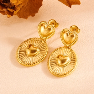 Detail of gold-plated stainless steel heart earrings with radiant texture on pink leather