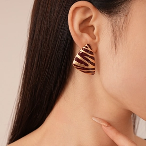 Gros plan de boucles d'oreilles triangles à motif zèbre en or et bordeaux