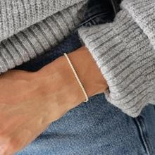 Gros plan d'un bracelet de tennis plaqué or avec des pierres de zircon brillantes au poignet