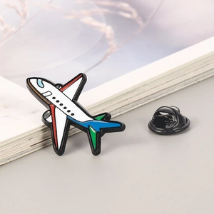 Close-up of 3D aircraft enamel pin with colorful wings on a minimalist background