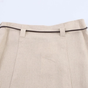 Dettaglio gonna in lino beige con cintura sottile marrone scuro e cerniera invisibile
