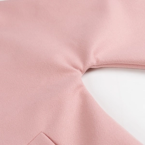 Détail d'un manteau en laine rose montrant la texture des fibres et les coutures