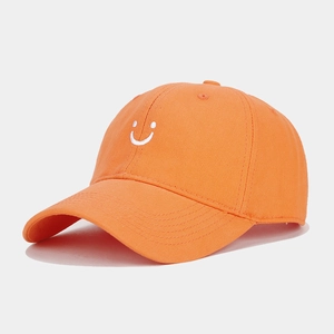 Close-up of bright orange baseball cap with high-quality white smiley face embroidery