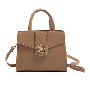 Petit sac carré kaki avec boucle fleurie dorée et bandoulière sur un fond blanc neutre