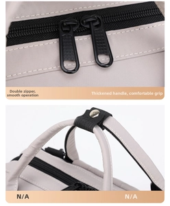 Detail of dual smooth zippers and reinforced padded handle on a light gray diaper bag