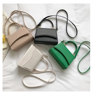 Flat lay of crocodile embossed mini tote bags in beige black white and green colors