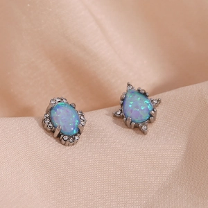 Gros plan de boucles d'oreilles rétro en opale bleue avec halo de cristal sur satin