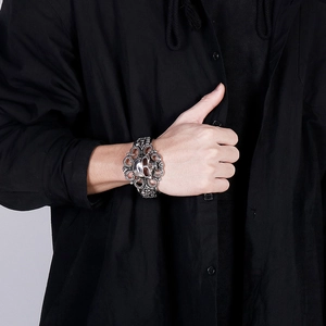 Détail d'un bracelet manchette large avec motifs de crânes évidés et volutes vintage