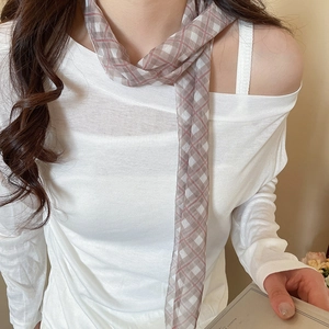 Close-up view of a thin brown plaid mesh scarf worn as a stylish and elegant neck accessory