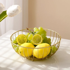 Modern gold wire metal fruit basket with fresh lemons and grapes in a minimalist home setting