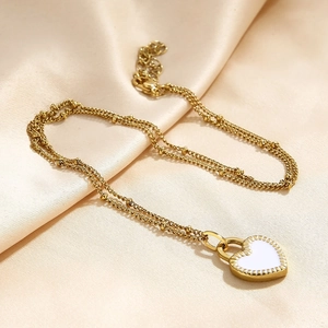 Detail of a gold-plated double-layer necklace with a white enamel heart-shaped pendant