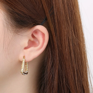 Close-up of gold U-shaped earrings with rhinestones worn by a model for a sparkling look