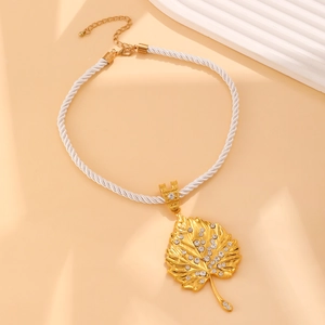 Detailed macro view of a gold-plated maple leaf pendant with sparkling rhinestones