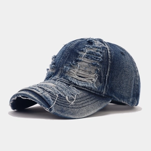 Detailed close-up of distressed denim baseball cap with vintage frayed holes and raw edges