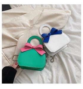 Detail of mini bags with bow decoration, round handles and ball chain straps