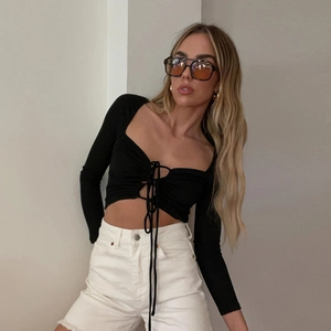 Dettaglio di un crop top nero a maniche lunghe con scollo a V profondo e lacci regolabili