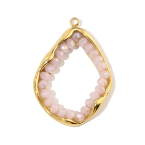 Close-up of a gold teardrop pendant with a faceted pink stone and intricate metal frame