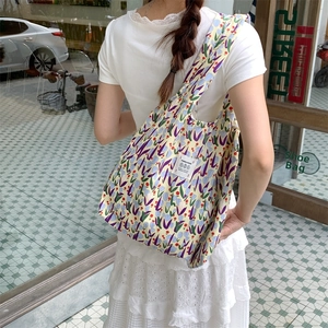 Dettaglio della borsa tote in tela floreale sulla spalla con motivi a fiori colorati