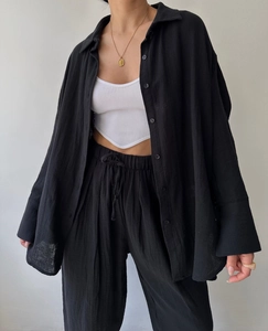 Detail of black oversized shirt and high waist trousers with ribbed white crop top vest