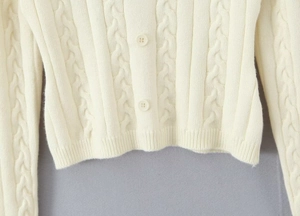 Détail du cardigan en maille torsadée crème avec boutons et texture de tricot fine