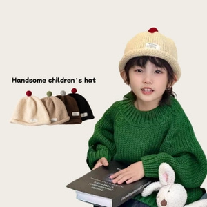Dettaglio di cappelli a maglia per bambini con pompon in beige, kaki, marrone e nero