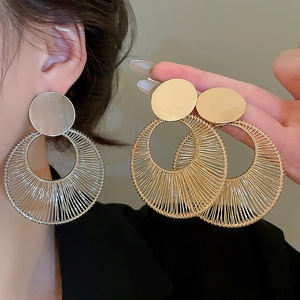 Close-up of geometric woven metal circle earrings in gold and silver finish