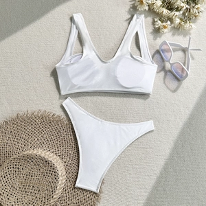 Detailed flat lay of a white ribbed bikini set with sunglasses and daisy flower decor