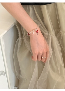 Detailed view of beaded strawberry bracelet with red heart charms on a model's wrist