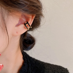 Close-up of double-layered C-shaped gold ear cuff with black enamel and zircons