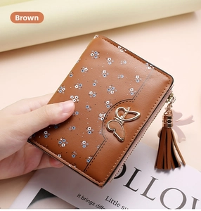 Close-up of brown floral short wallet with gold butterfly charm and side tassel detail