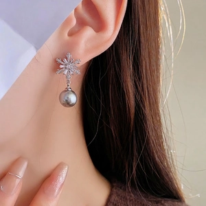Silver snowflake earrings with zircon and gray pearl shown on a model with soft lighting