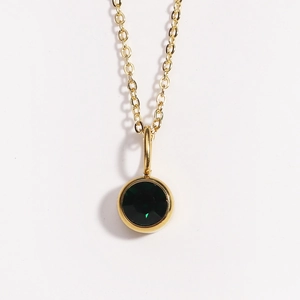 Detailed close-up of a round deep green birthstone pendant on a gold chain necklace